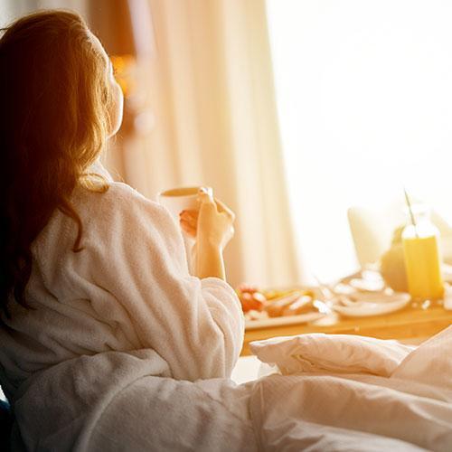 Woman sitting on bed having breakfast
