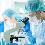 Man and woman looking into microscopes in clinical setting