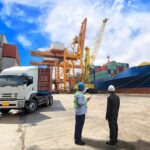 Two men dockside with a cargo ship
