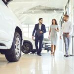 Motor trader talking to couple in car showroom