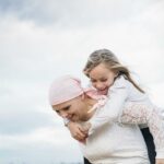 Woman in headscarf giving girl a piggyback