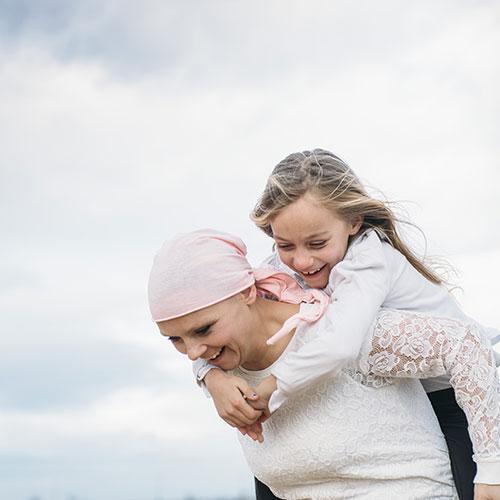 Woman in headscarf giving girl a piggyback