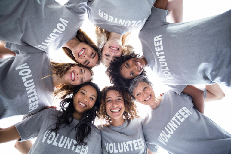 Charity Volunteers huddles in a circle, looking down at you and smiling.